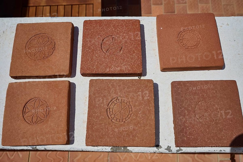 Six square clay bricks with different geometric and floral patterns laid on a white table top, Patmos Cotto brickworks, traditional brick making, Kampos, Patmos, Dodecanese, Greek Islands, Greece, Europe