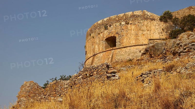 An old, round stone tower stands on a hill with overgrown vegetation, Venetian sea fortress, Leper Island, Spinalonga, Elounda Bay, Mirabello Bay, East Crete, Crete, Greek Islands, Greece, Europe