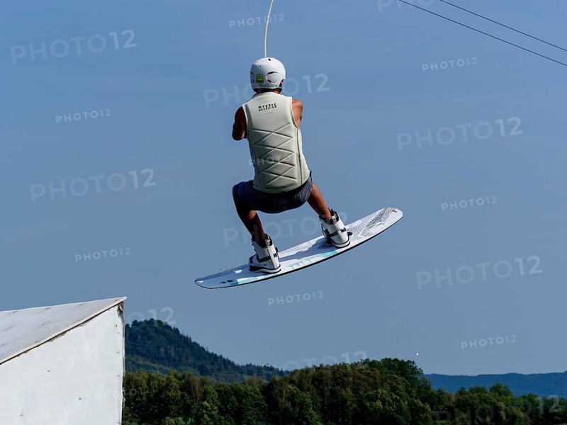 Young man jumping with wakeboard over jump and obstacle, water sports, water skiing in wakepark, Stráž pod Ralskem, Czech Republic, Europe
