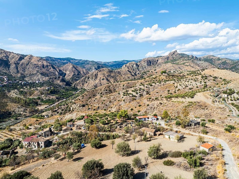 Mountains and Olive groves around Ghost Town from a drone, Pentedattilo Village, Calabria, Italy, Europe
