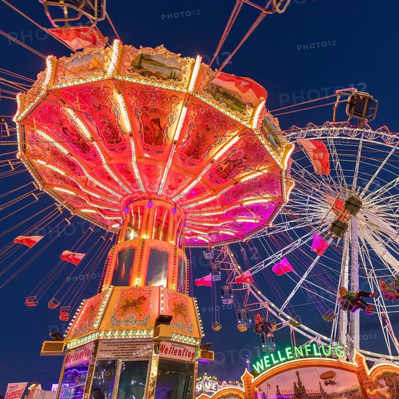 A funfair at dusk with illuminated chain carousel and Ferris wheel, Europa Rad, rides, wave flight, Cannstatter Wasen, folk festival, Bad Cannstatt, Stuttgart, Baden-Württemberg, Germany, Europe
