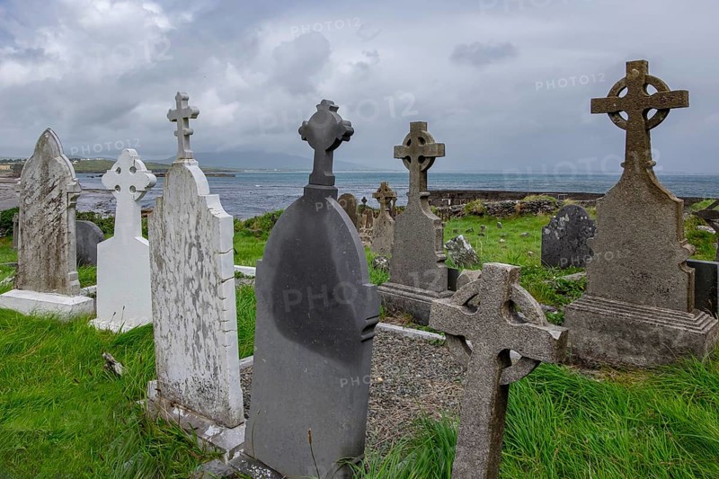 Coast with old gravestones against a cloudy sky and sea background, cemetery near Ballinskelligs Abbey, County Kerry, Ireland, Europe