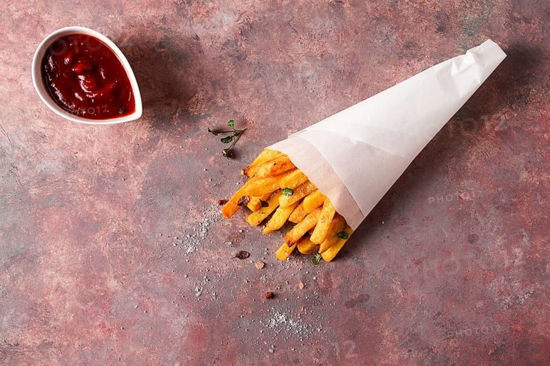 Fried French fries, in a paper bag, on an abstract background, no people, rustic