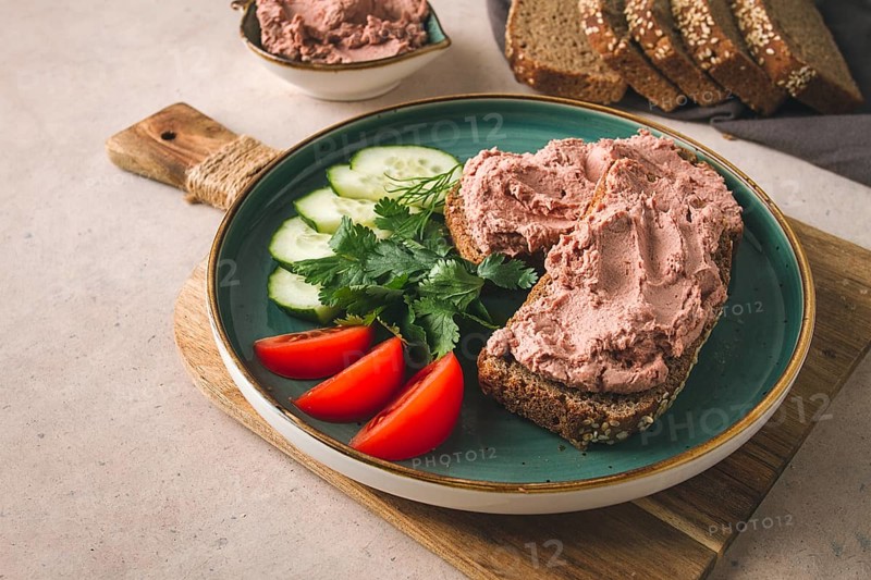 Liver meat pate spread on rye bread, breakfast, close-up, beige background. no people, selective focus