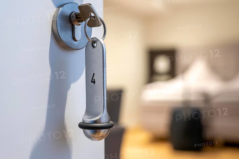 Symbolic image of a hotel, key inserted in the door of a hotel room, analogue lock