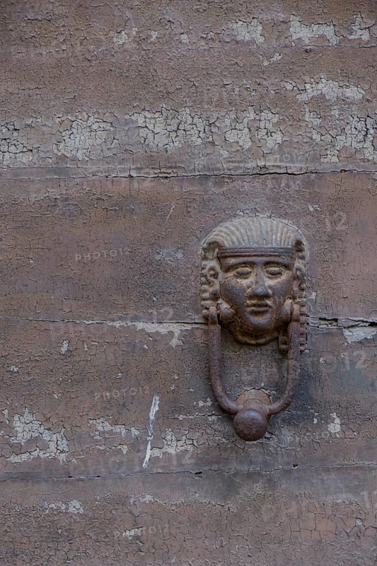 Old door knocker in the shape of a face on a weathered stone surface, Galatina, Apulia, Italy, Europe