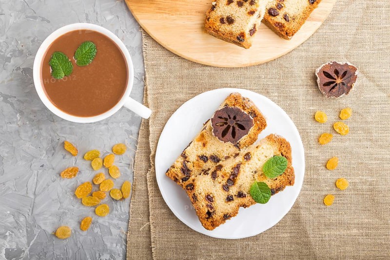 Homemade cake with raisins, dried persimmon and a cup of hot chocolate on a gray concrete background and linen textile. top view, flat lay, close up