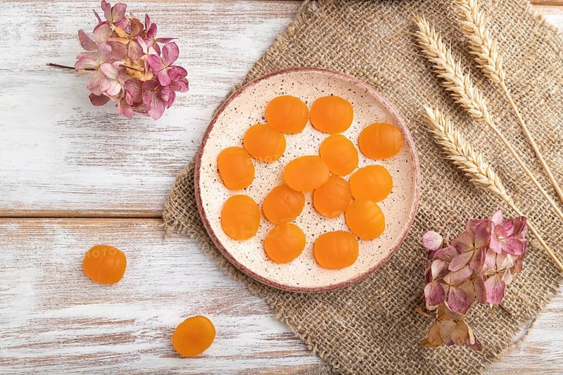 Jelly pumpkin candies on white wooden background and linen textile. close up, top view, flat lay. autumn concept