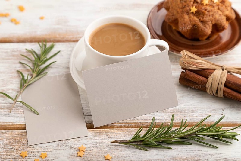 Gray paper business card mockup with cup of coffee and cake on white wooden background. Blank, side view, still life
