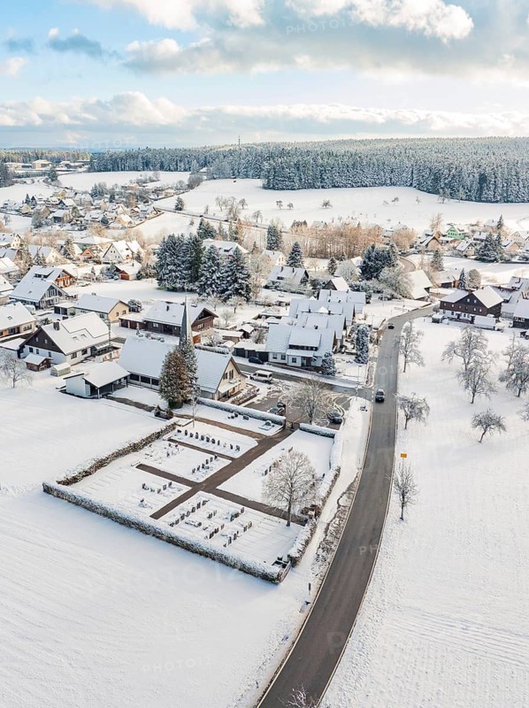 Snow-covered village with church and surrounding snow-covered buildings, Oberreichenbach, Black Forest, district of Calw, Germany, Europe