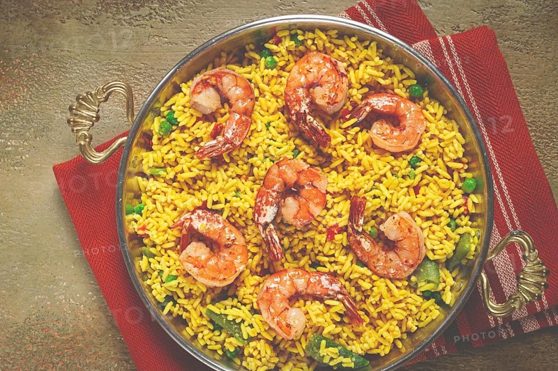 Rice with saffron and shrimp, in a frying pan, paella with shrimp, top view, homemade, no people