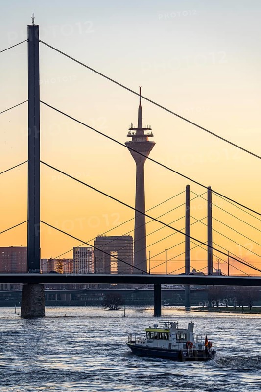 Sunset on the Rhine near Düsseldorf, skyline of the city centre with Rhine Tower, Rheinkniebrücke, behind, Oberkassler Brücke, boat of the water police, North Rhine-Westphalia, Germany, Europe