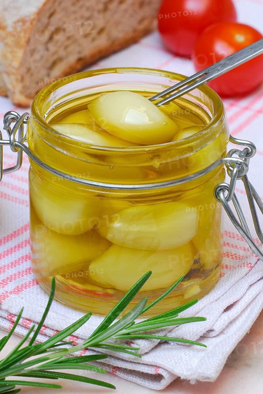 Garlictoes (Allium sativum) in olive oil, with rosemary
