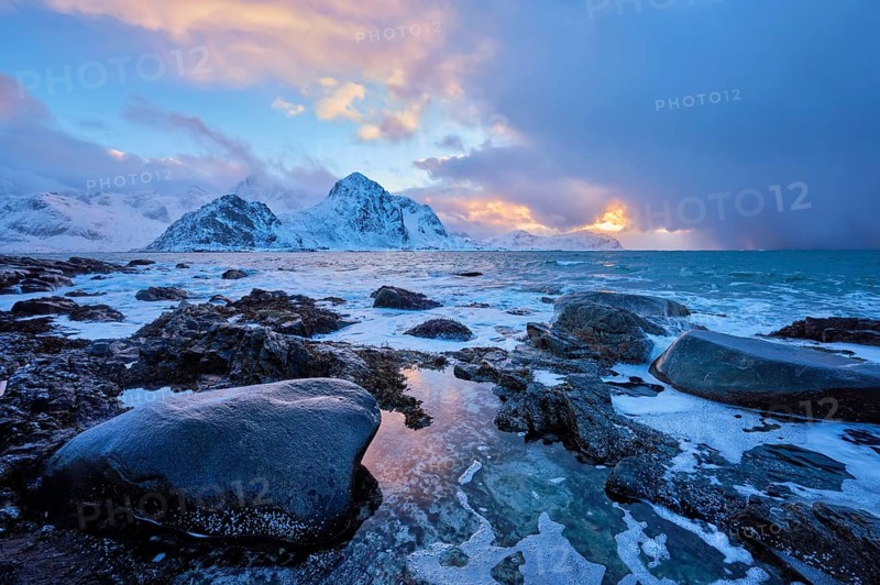 Beach of Norwegian sea on rocky coast in fjord on sunset in winter. Vareid beach, Lofoten islands, Norway, Europe