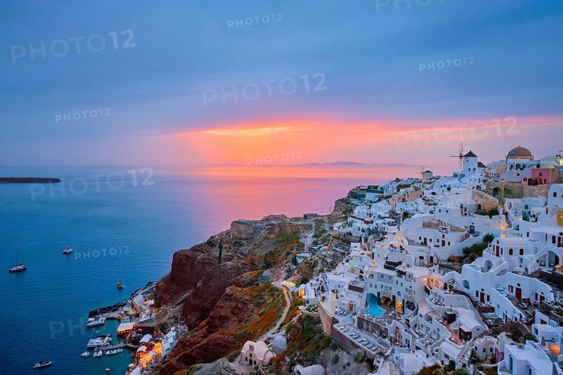 Famous greek iconic selfie spot tourist destination Oia village with traditional white houses and windmills in Santorini island on sunset in twilight, Greece, Europe