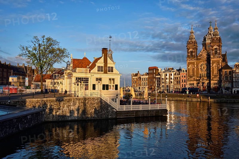 AMSTERDAM, NETHERLANDS, MAY 9, 2017: Tourist information center, Amsterdam canal and Church of Saint Nicholas (Sint-Nicolaaskerk) on sunset. Amsterdam, Netherlands
