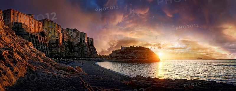 Panorama on the beach Lido Le Roccette Club Tropea with the old town of Tropea situated on rocks of sandstone and the medieval church Santuario di Santa Maria dell Isola at sunset and luminous cloudy sky, Tropea, Vibo Valentia, Calabria, Southern Italy, Italy, Europe