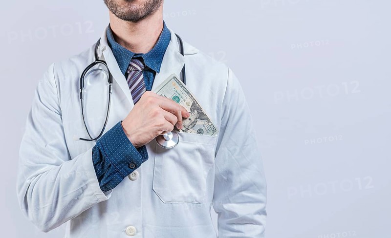 Corrupt doctor putting bribe money in pocket isolated. Dishonest doctor putting money in pocket, Medical bribery concept