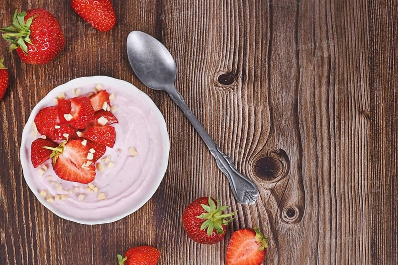 Strawberry yogurt bowl on wooden desk with berries