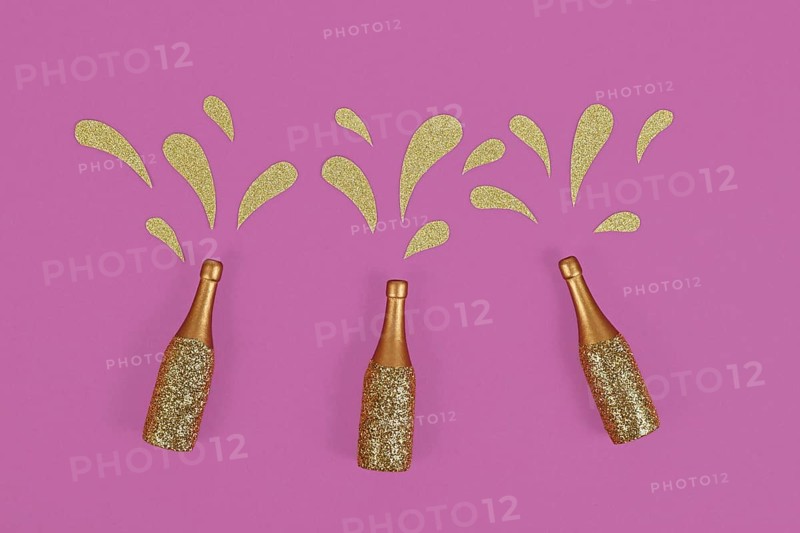 Three golden splashing Champagne bottles on purple background