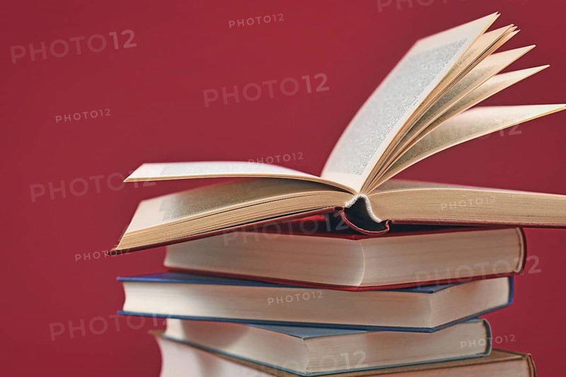 Stack of old hardcover books on dark red background