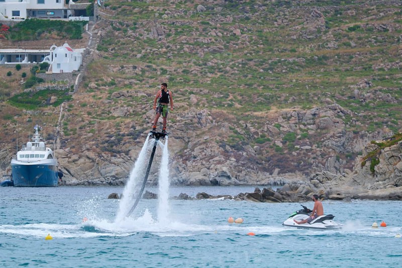 MYKONOS, GREECE, MAY 29, 2019: Man flying flyboarding on a Flyboard, hydroflighting device which supplies propulsion to drive the Flyboard invented by inventor Franky Zapata