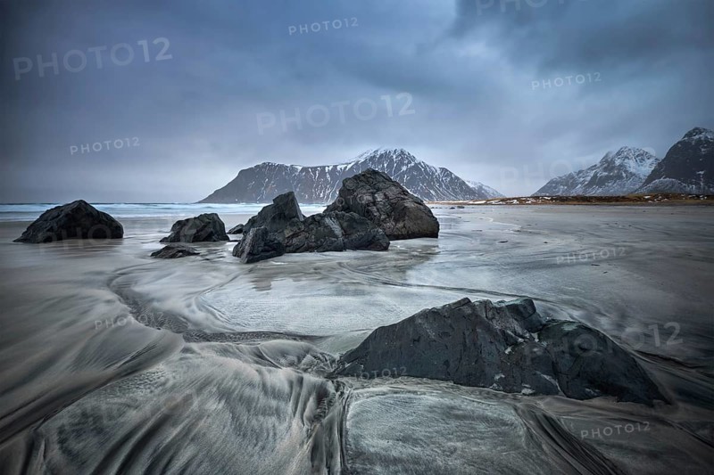 Rocks on Norwegian sea beach in fjord. Skagsanden beach, Flakstad, Lofoten islands, Norway. Long exposure motion blur