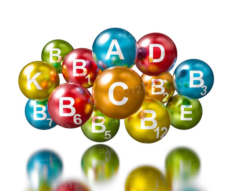 Vitamins concept -spherical pills with vitamin names on white with reflection