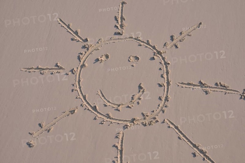 Sun face drawn in the sand