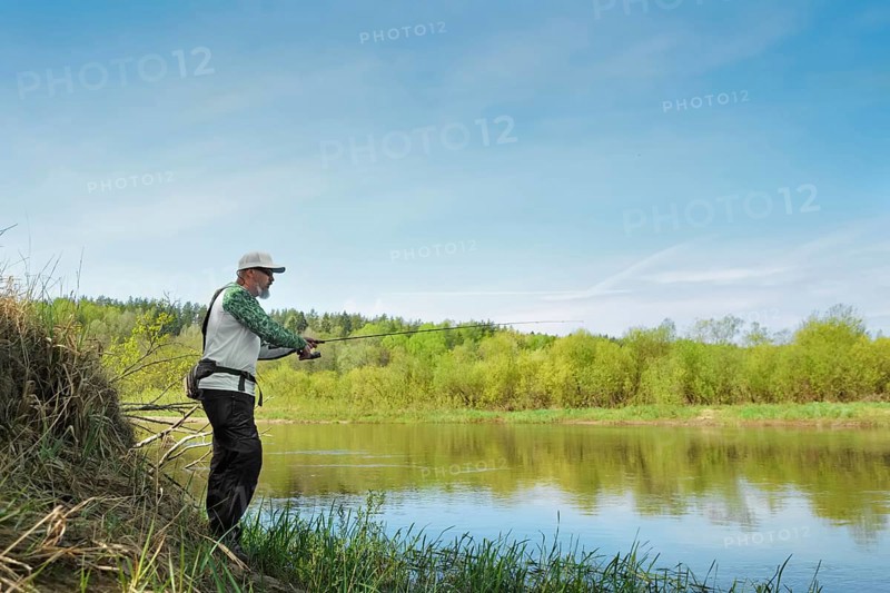 Fisherman trying to do a perfect cast, throwing lure. Spining fishing, angling, catching fish. Hobby and vacation. Photo with shallow depth of field taken at wide open aperture