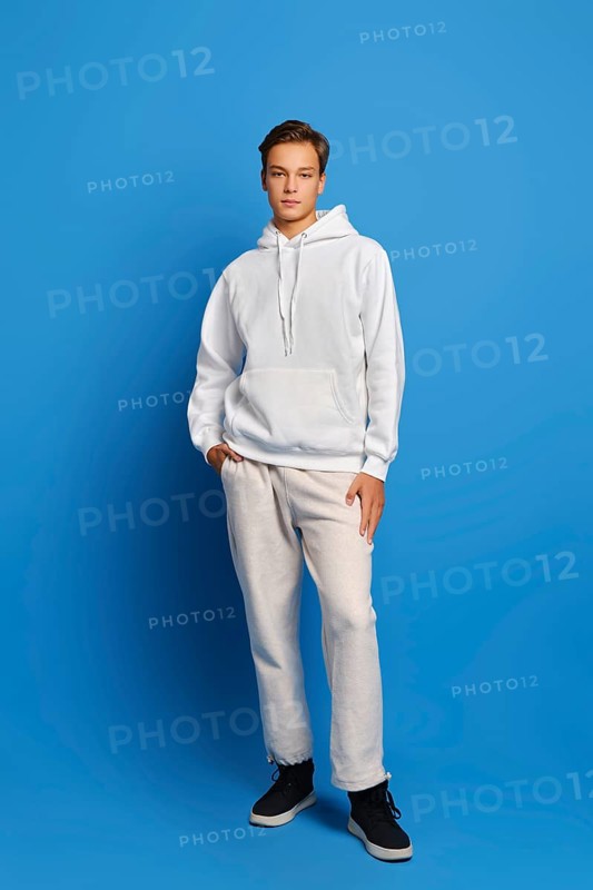 Attractive stylish man wearing white sweatshirt and sweatpants standing over blue studio background