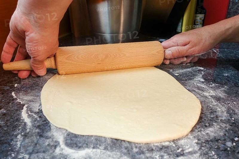 Swabian cuisine, preparation of mini dinnete, also dennete, dinnede, denetle, rolling out raw yeast yeast dough, yeast pastry, baking, from the oven, typical Swabian reinterpreted, party pastry, finger food, appetisers for on the go, traditional cuisine, rolling pin, flour, worktop, men's hands, food photography, studio, Germany, Europe