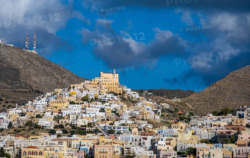 View of the town of Ermoupoli with pastel-coloured houses, on the hill Basilica of San Giorgio in Ano Syros, dramatic cloudy sky, Ermoupoli, Syros, Cyclades, Greece, Europe