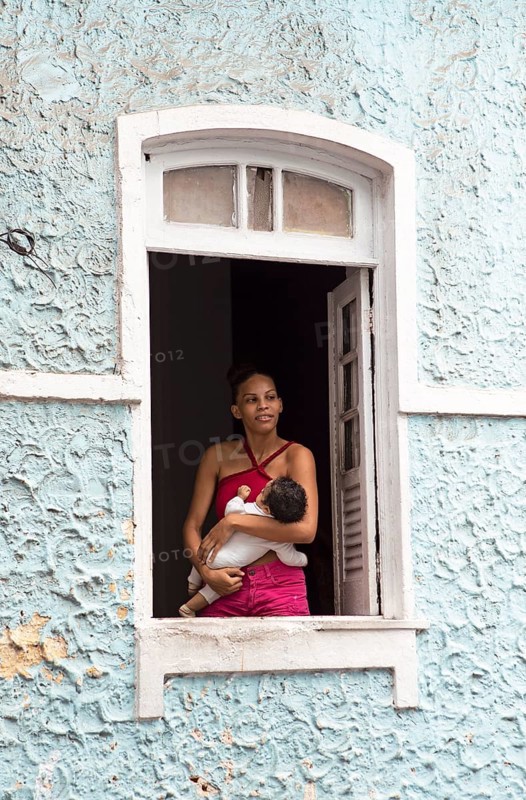 Brazilian woman with baby in her arms standing at a window, historic old town, Salvador, state of Bahia, Brazil, South America