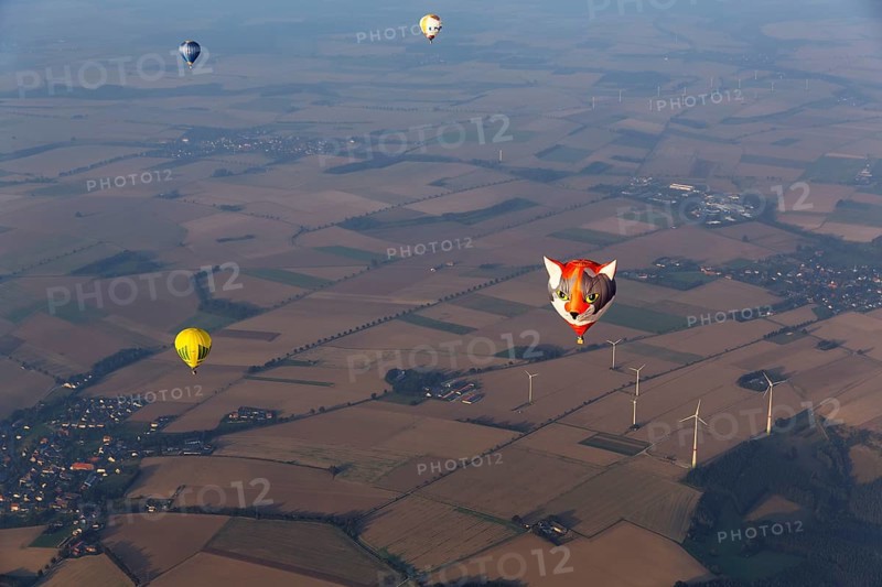 Hot-air balloons in the evening haze, advertising, view of villages, fields and wind turbine, hot-air balloon festival, 26th Warsteiner International Montgolfiade, aerial view, Warstein, Sauerland, North Rhine-Westphalia, Germany, Europe