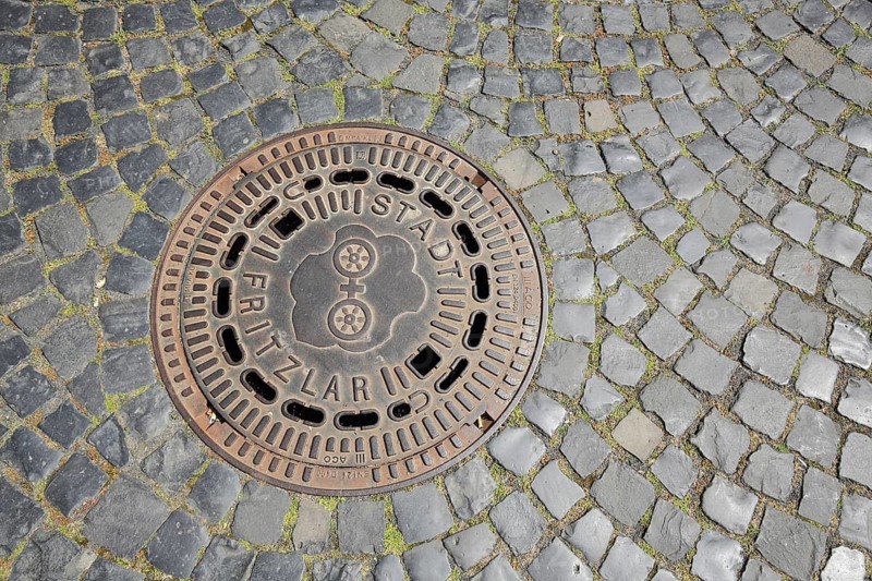 Manhole cover with city coat of arms and inscription, city, paving stones, market place, Fritzlar, Hesse, Germany, Europe