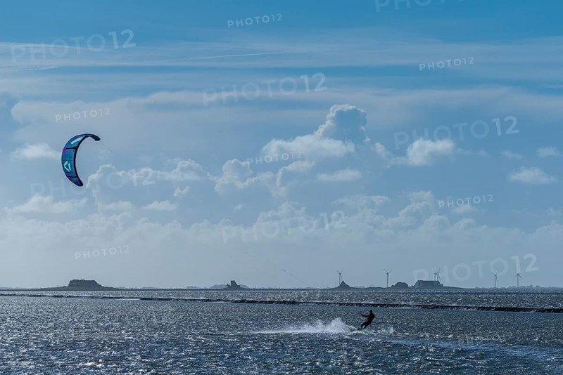 Kitesurfing on the North Sea, Lüttmoorsiel, Reußenköge, on the horizon Hallig Nordstrandischmoor, Lorendamm, wind power, wind force 6, blue sky, North Frisia, Schleswig-Holstein, Germany, Europe
