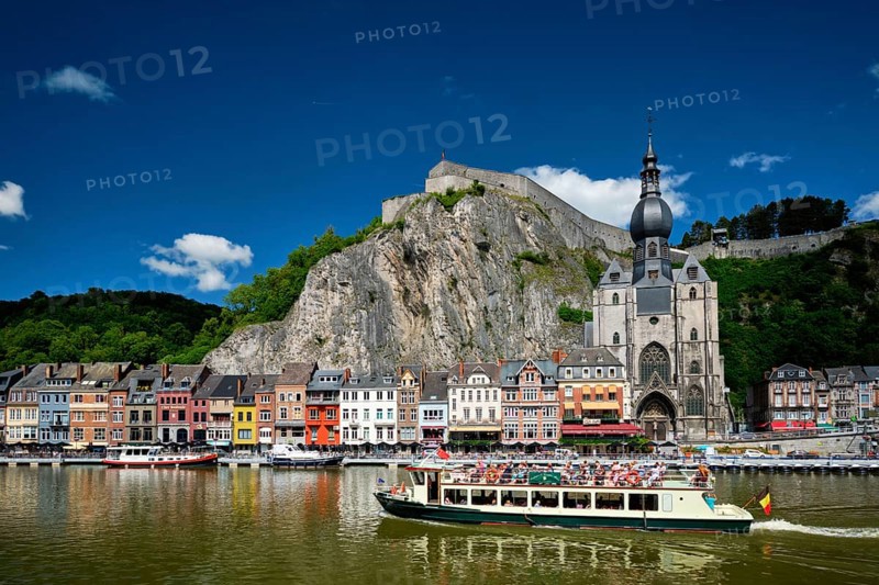 DINANT, BELIGUM, MAY 30, 2018: View of Dinant city over the Meuse river with tourist boat. Dinant is a Walloon city and municipality located on the River Meuse, in the Belgian province of Namur