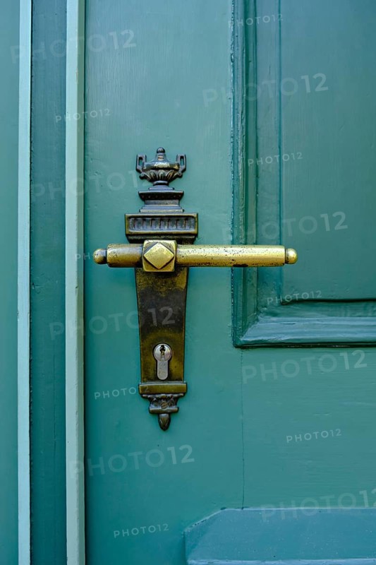 Old historical door handle on a green door