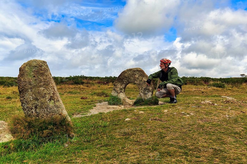 Mên-an-Tol, Men an Tol, cyclist beside perforated stone in a field, Bronze Age megalith, Penzance, Cornwall, England, Great Britain