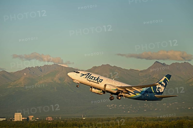 Against the backdrop of the Chugach Mountains and the houses of Anchorage, an Alaska Airlines cargo plane takes off from Ted Stevens International Airport, Anchorage, Alaska