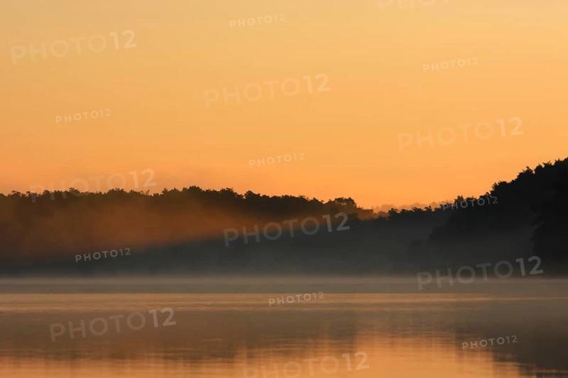 Foggy mood with a ray of light from the rising sun over a lake in Mecklenburg, Müritz National Park, Mecklenburg-Vorpommern, Germany, Europe