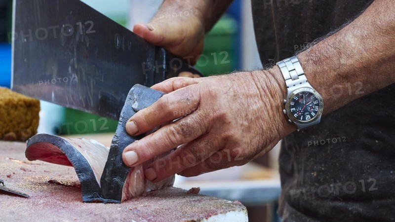 Man cuts tuna into strips with large knife, fish market, old town, Catania, east coast, Sicily, Italy, Europe