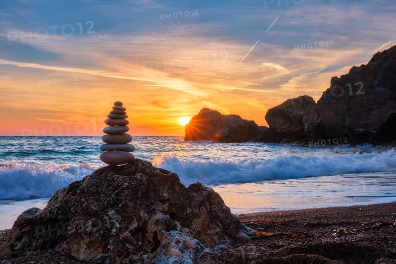 Concept of balance and harmony. Cairn stack of stones pebbles cairn on the beach coast of the sea in the nature on sunset. Meditative art of stone stacking