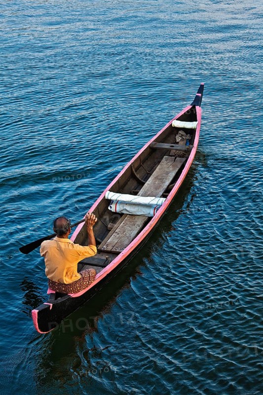 KERALA, INDIA, MAY 5, 2010: Indian man in small canoe boat in backwaters. Kerala backwaters are both major tourist attraction and integral part of local people life in Kerala