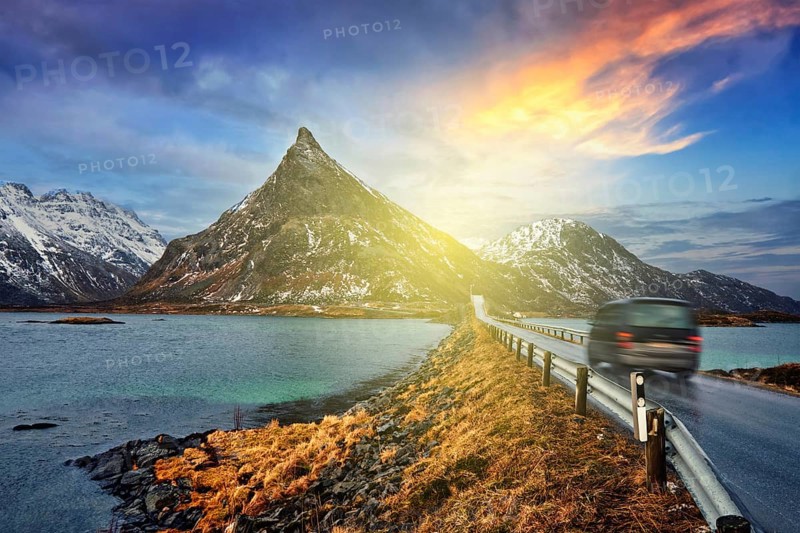 Car on road in Norwegian fjord on sunset. Lofoten islands, Norway. With motion blur