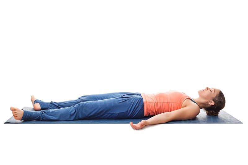 Beautiful sporty fit yogini woman relaxes in yoga asana Savasana, corpse pose isolated on white