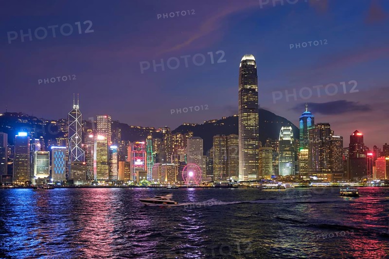 Hong Kong skyline cityscape downtown skyscrapers over Victoria Harbour in the evening illuminated with tourist boat ferries, Hong Kong, China, Asia