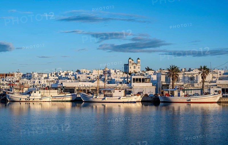 View of Naoussa, Fishing boats in the harbour at sunset, reflected in the sea, White Cycladic houses and church Agios Faneromeni, Naoussa, Paros, Cyclades, Greece, Europe