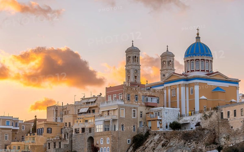 View of the village with the Greek Orthodox church of Agios Nikolaos, Asteria Beach, at sunset with atmospheric clouds, Ermoupoli, Syros, Cyclades, Greece, Europe